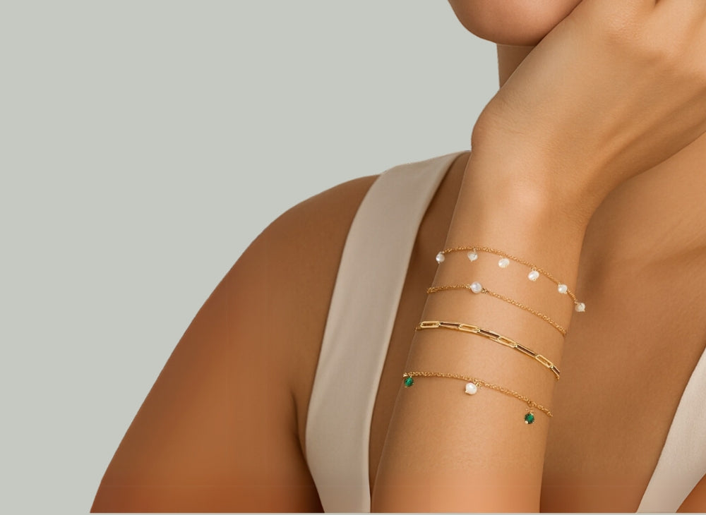 A model wearing a stunning stack of four different bracelets from MS Gems by Mamta, showcasing how to layer a classic tennis bracelet with a chain and pearl bracelets.